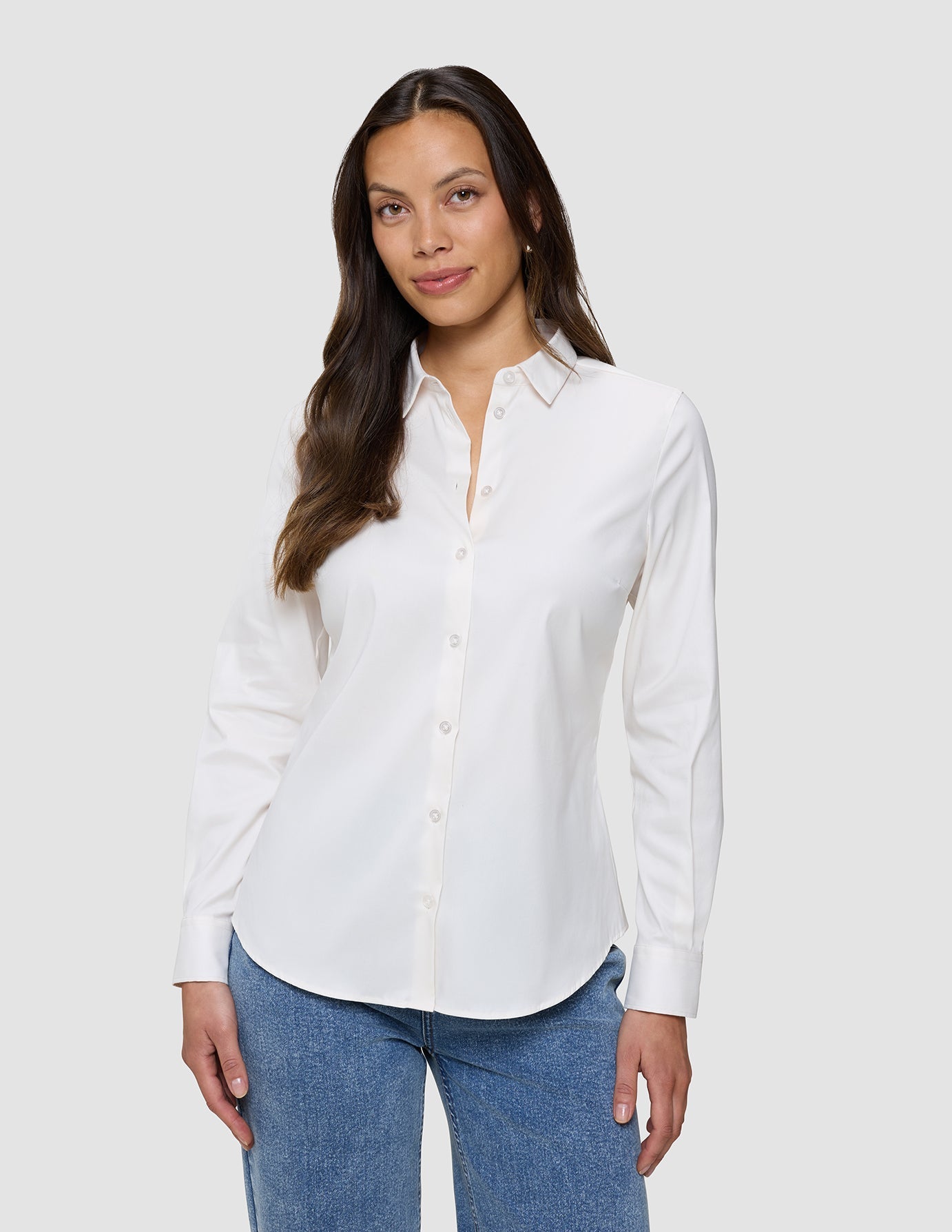 Eine Frau, die ein weißes Damen-Oxford-Hemd White Orchid Slim mit klassischem Kragen und eine blaue Jeans trägt.
